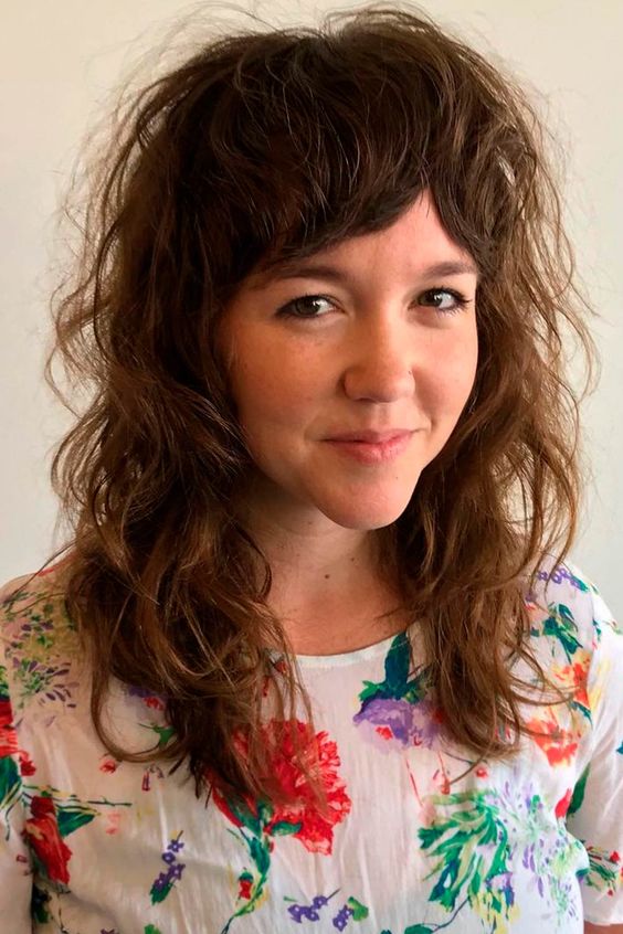 a voluminous wavy wolf cut with bottleneck bangs on naturally wavy hair is a super cool idea