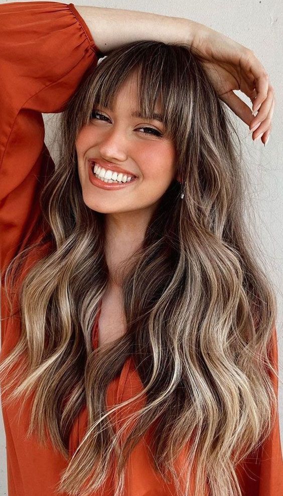 long brunette hair with blonde balayage and bottleneck bangs is a cool and lovely solution