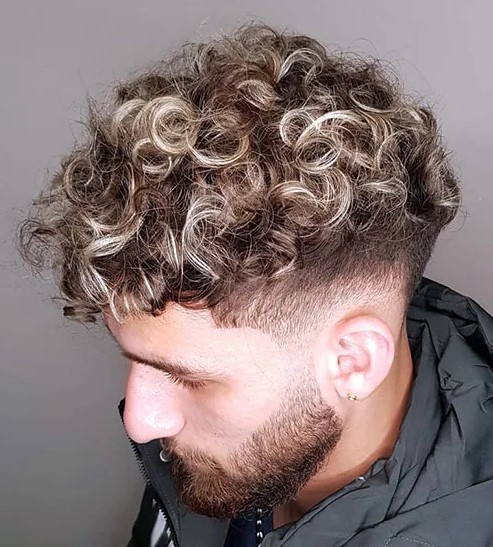 losse blonde curls with low taper and a beard look daring and cool, and curly texture makes them edgy