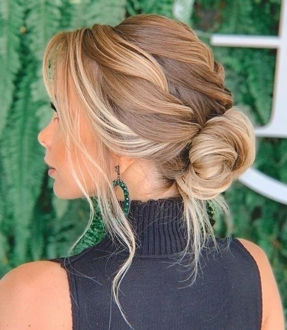 a beautiful and a bit messy low bun with a braided top, waves framing the face is adorable