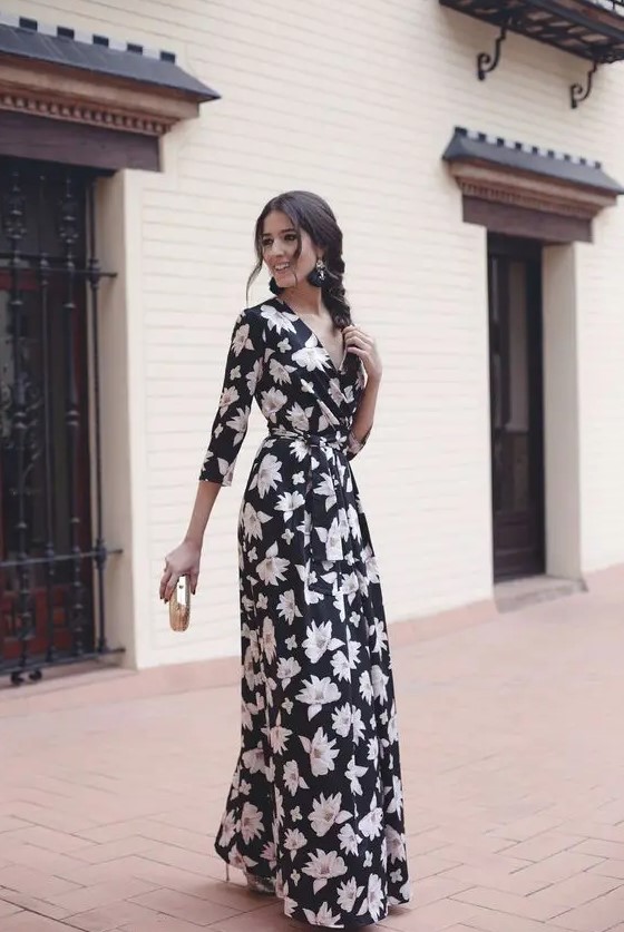 A black floral maxi dress with long sleeves and a V neckline, black tassel earrrings, metallic shoes and a clutch