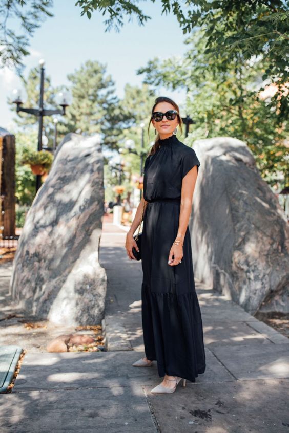 a black maxi dress with a high neckline, grey lace up shoes and a small black bag for a fall wedding