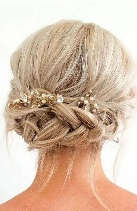 a braided updo with a bump on top and pearl and rhinestone hairpieces, some locks down is a creative idea for medium hair