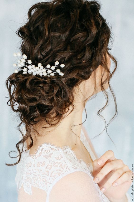 a chic and cool curly low bun with curls on top and down to frame the face, a large pearl hair pin for an accent