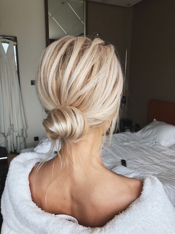 a classic low bun with a volume on top and some locks down is a cool idea for a modern bridesmaid look
