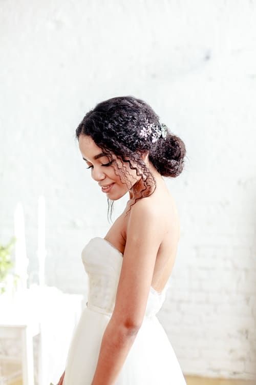 a curly low bun with curls accenting the face and a lovely floral hairpiece is a classic idea