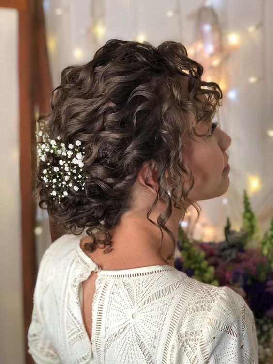 a curly low updo with curls down and baby's breath is a stylish and lovely idea for a romantic boho bride