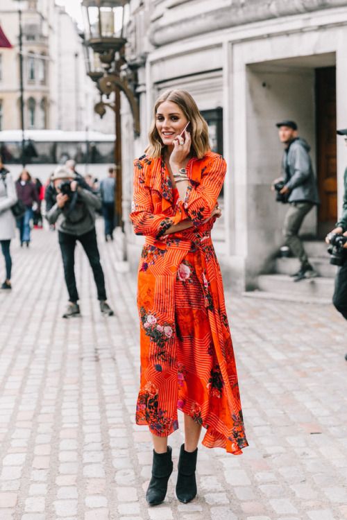 a bright orange midi dress with ruffles and a floral print, black booties are a super bold and catchy fall wedding guest look