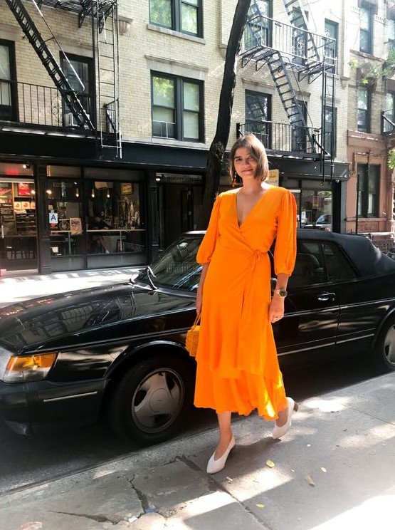 a bright orange midi wrap dress with long sleeves, trendy white shoes and a small bag