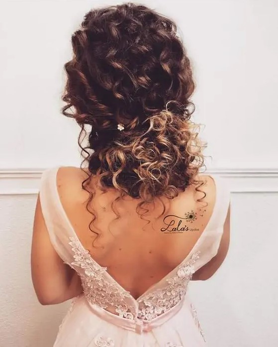 a curly low updo with locks down and twists with a single floral hairpin will add romance to your look