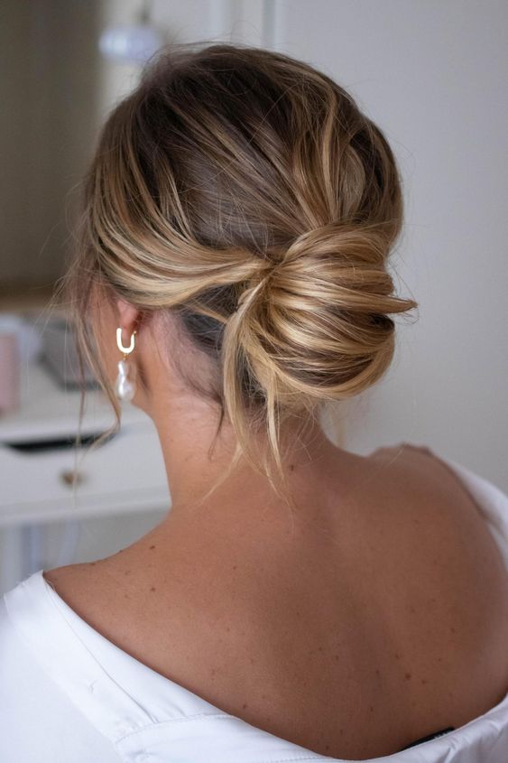 a messy chignon with a messy top and waves down is a chic modern solution for a bridesmaid