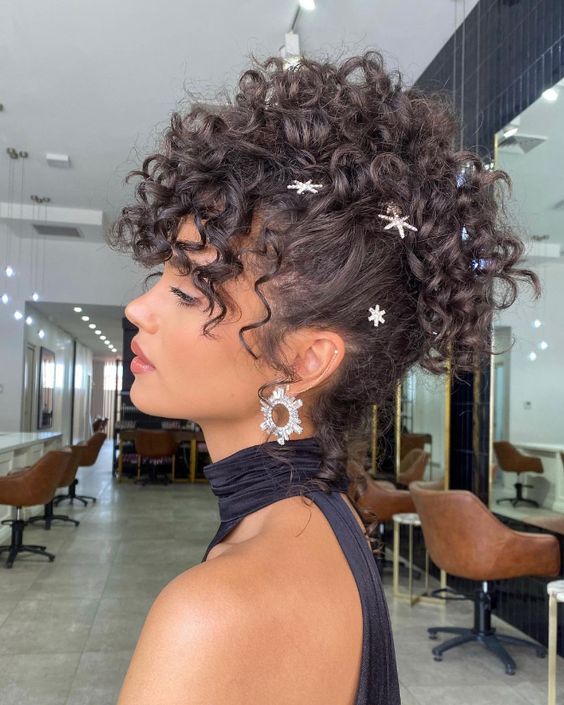 a curly mohawk updo with curls on top and some shiny rhinestone hair pins all over the head is cool
