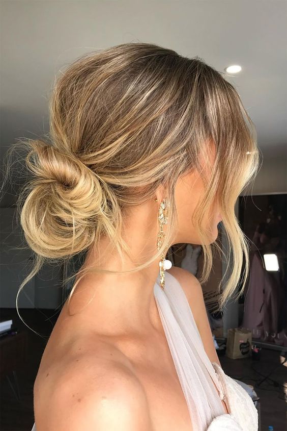 a messy low bun hairstyle with a messy bump on top, some waves down is a cool idea for an effortlessly chic look