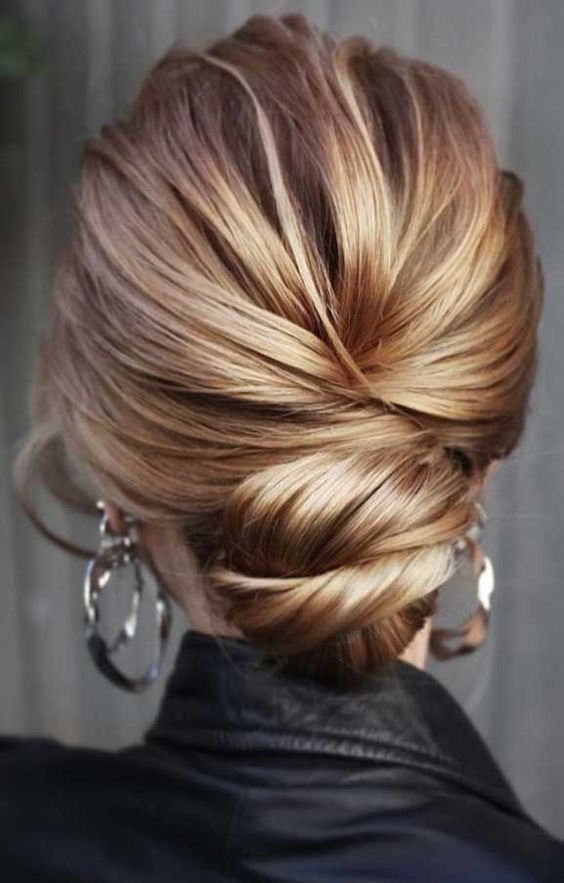 a modern twisted low bun with a volume on top is a stylish and catchy hairstyle for a modern bride