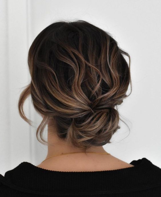 a messy wavy low bun with a wavy top and waves framing the face is a cool solution for a bridesmaid look