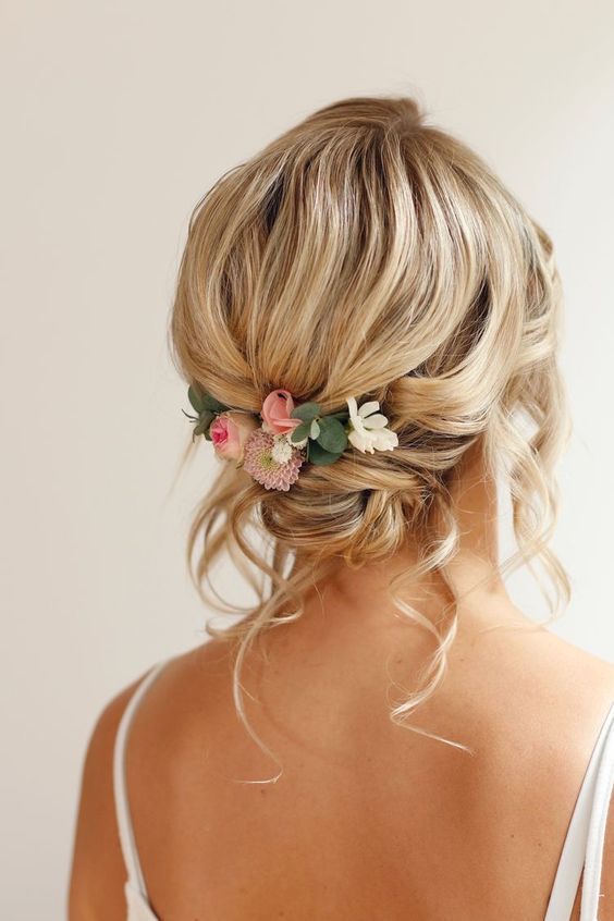 a romantic loose updo with a volume on top and a low bun, some waves down and fresh blooms is a lovely idea for medium hair