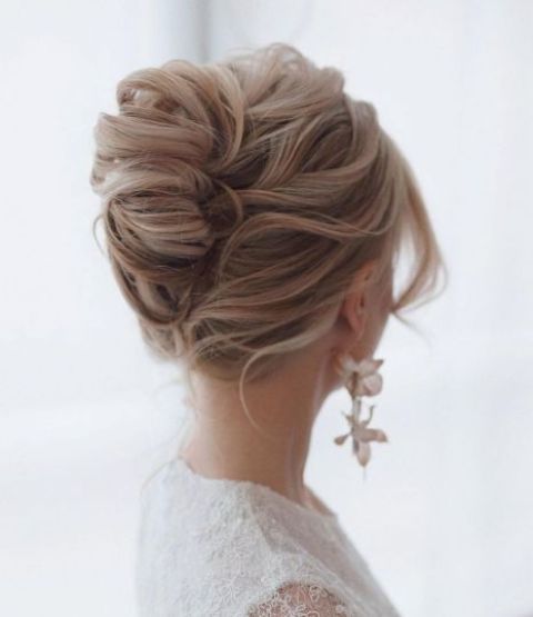 a lovely twisted chignon with a messy top and waves framing the face is a relaxed and effortless hairstyle