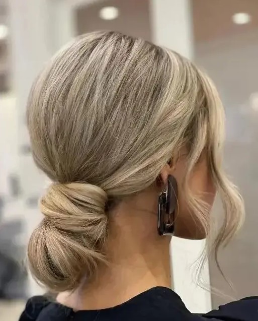 a wrapped low bun with a bump on top and some waves around the face is a super modern and chic idea