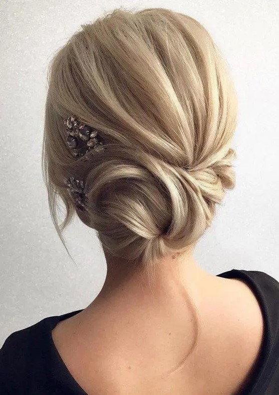 a low side swept twisted chignon with some bangs and a rhinestone hairpiece for an accent