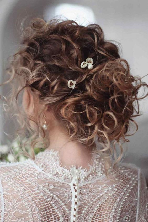 a messy curly updo on medium hair, with messy curls all over and some blooms is a chic and always actual idea
