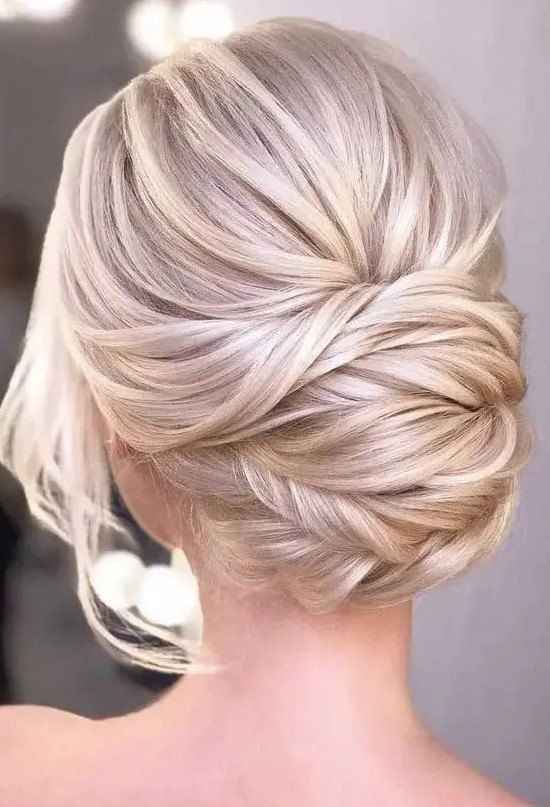 a beautiful blonde twisted low chignon with a bump on top and some locks down is a chic and formal idea