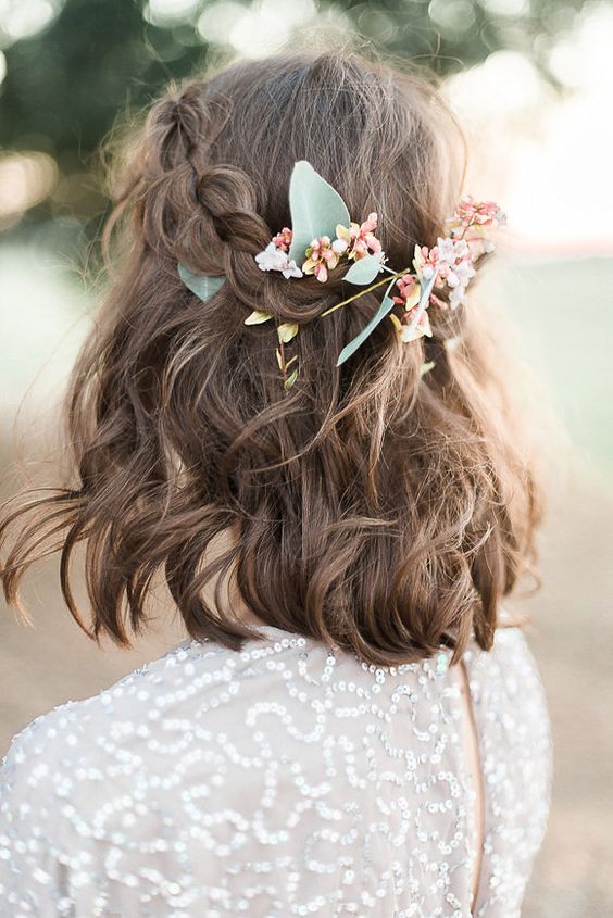 a boho half updo with a braided halo and waves down, some fresh blooms and greenery is a cool idea for a bridesmaid