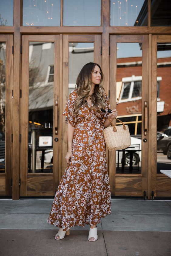 a pretty rust-colored floral maxi dress with short sleeves, white mules, a basket bag for a relaxed wedding guest look