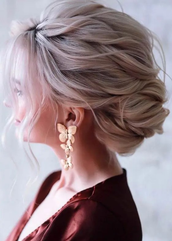 a beautiful and dimensional low French twisted updo with a wavy and textural top and some waves down is awesome