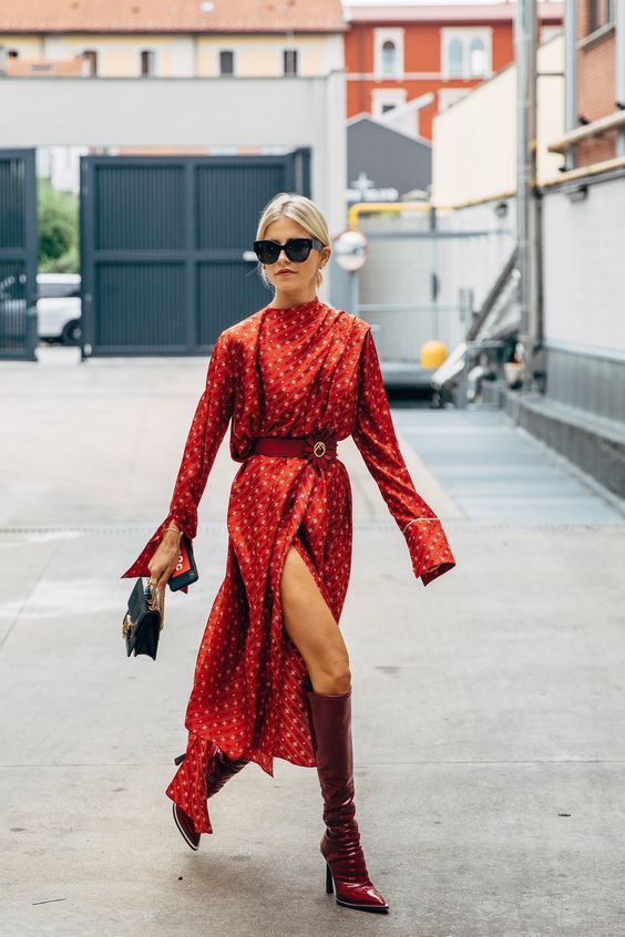 a red printed midi dress with a slit and a belt with an embellished buckle, red boots and a small black bag