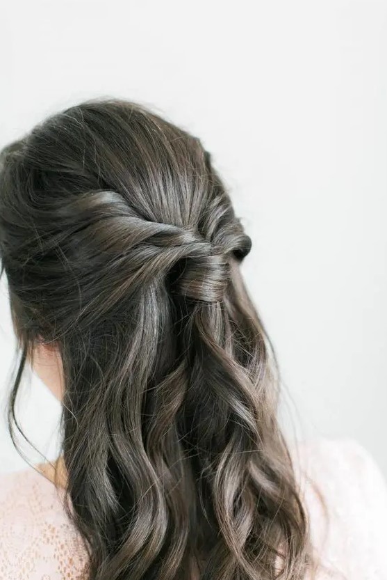 a boho half updo with a sleek top, a twisted ponytail and waves down is a lovely solution