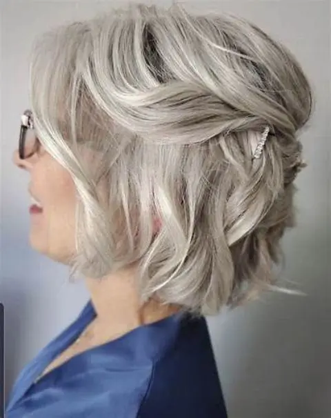 a lovely half updo with a bump on top and some messy waves, plus a lot of volume and a rhinestone hair pin