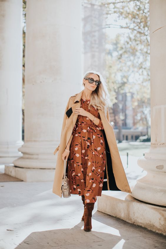 an elegant fall wedding guest look with a brown printed midi dress, burgundy velvet boots, a beige coat and a neutral bag