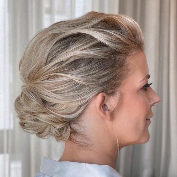 a pretty wavy updo with a small low bun with a voluminous and wavy top is a chic idea for a mother of the bride