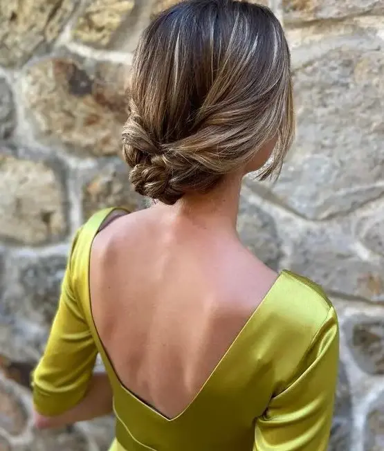 A refined braided low updo with a sleek top and face framing locks is a stylish idea for mothers with long hair