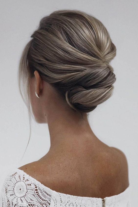 A refined twisted updo with a bump on top and a lot of volume, face framing locks is a stylish idea for a mother of the bride