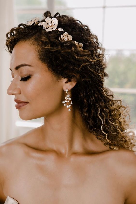 a curly half updo with a floral hairpiece is a romantic and delicate idea for a wedding