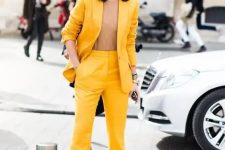 50 a bright yellow suit with flare pants, a camel top that matches the skin and a small clutch