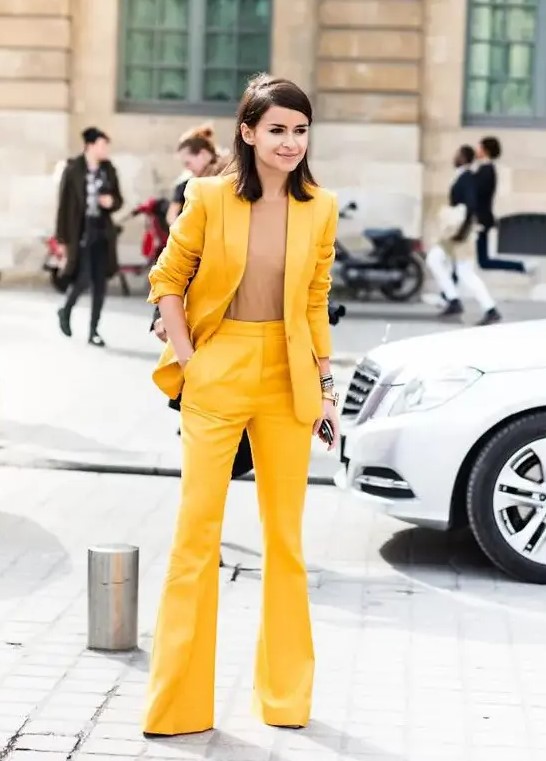 a bright yellow suit with flare pants, a camel top that matches the skin and a small clutch