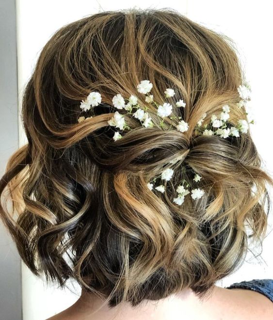 a pretty twisted half updo with waves and baby's breath tucked in is a great idea for a boho or rustic wedding