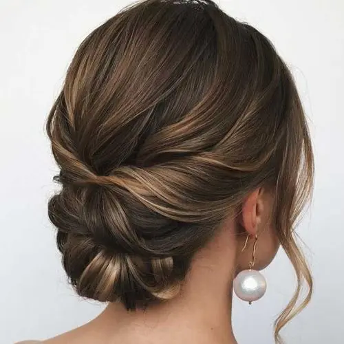 a stylish twisted low updo with a volume on top and waves framing the face is an elegant idea for a mother of the bride