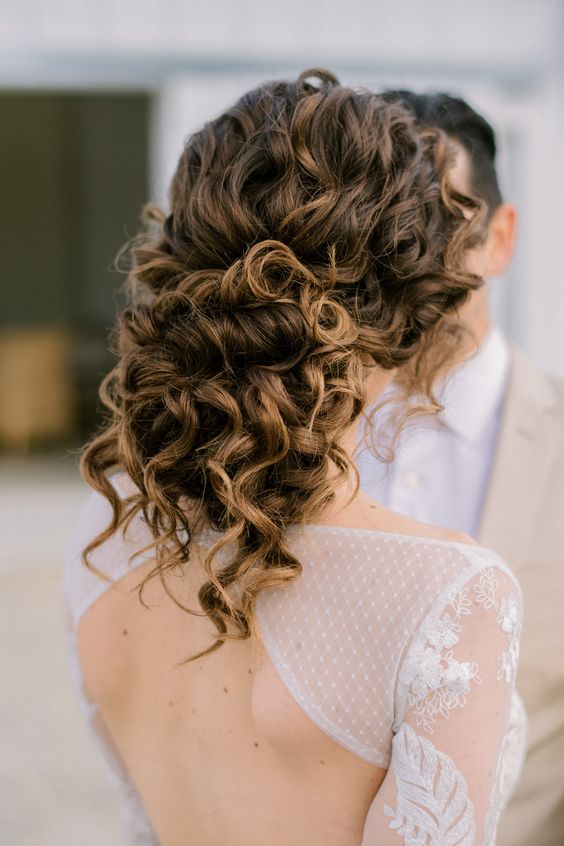 a messy curly half updo with a curly top and some curls down is an elegant and stylish solution for a romantic bridal look
