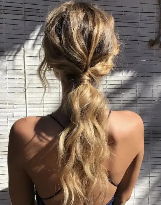 a wavy messy low ponytail with some locks down is great for a casual rehearsal dinner or a casual wedding