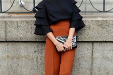 55 a refined fall wedding guest outfit with a black top with ruffle sleeves, rust pants and black shoes plus a black embellished bag