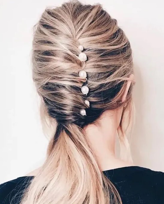 a catchy low ponytail with a twist and several pearl pins for a modern take on classics