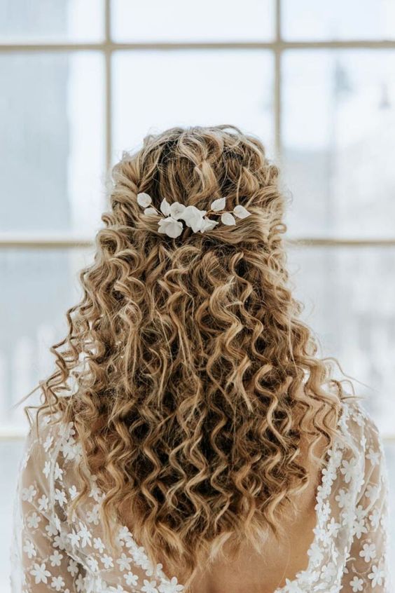 a simple and cool curly half updo with a curly top and curls down and some white blooms accenting is a lovely idea