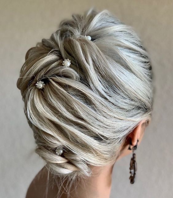 An eye catchy updo with twists and volumes secured with pearl hair pins is a stylish idea for a mother of the bride