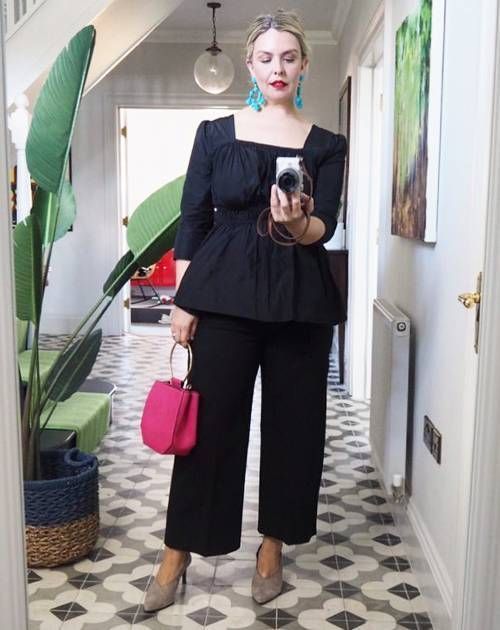 an eye-catching black outfit with a square neckline top, wideleg pants, grey shoes, a hot pink bag and statement earrings