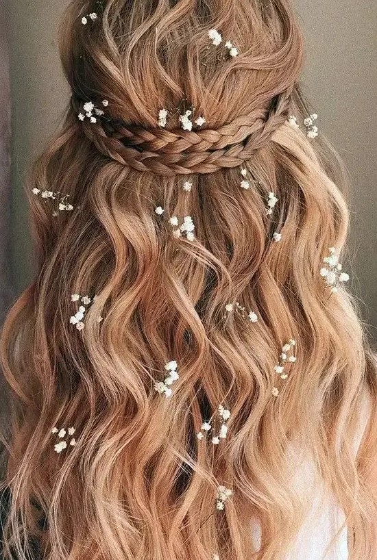 a lovely half updo with a braided halo, waves down and some baby's breath tucked into the hair is idea for summer