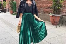 63 a black top with a lace neckline, a black cropped leather jacket, a green metallic pleated midi skirt, black heels