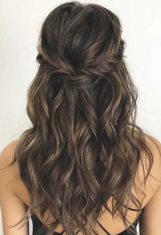 a messy and textured half updo with a fishtail braided halo, a bump on top and waves down is wow